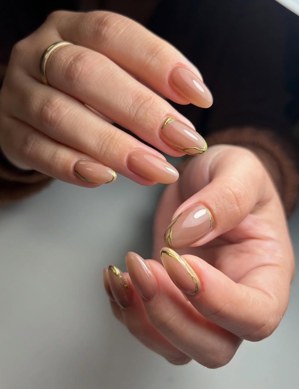 Unhas para o Ano Novo apresentam um design elegante com esmalte nude, realçado por uma fina linha dourada na borda. Este estilo combina sofisticação e modernidade, perfeito para as celebrações de fim de ano.