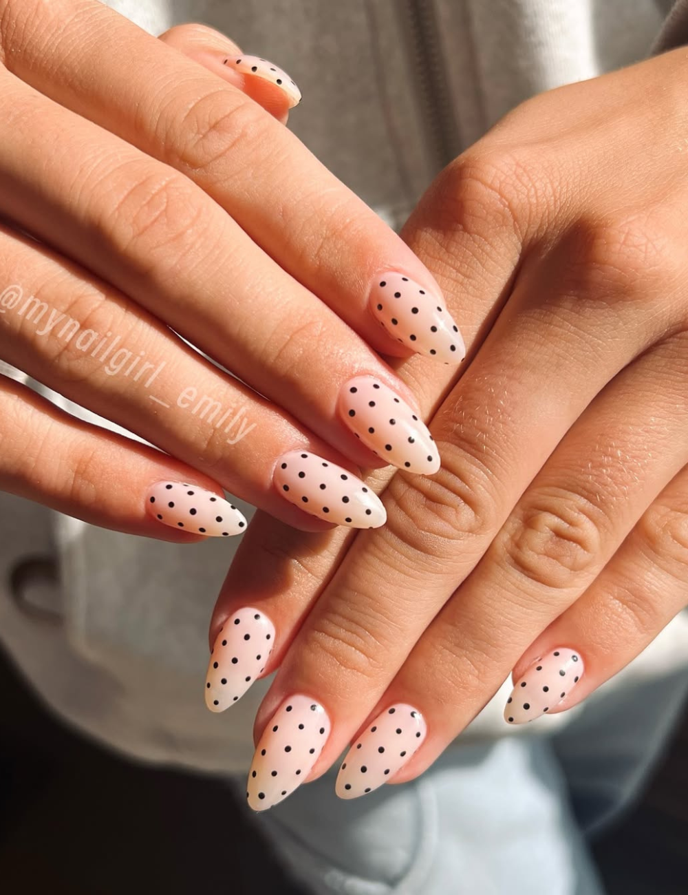 Unhas para o Ano Novo apresentam um design elegante com esmalte em tom nude e delicados poás pretos. O formato stiletto confere um toque moderno e sofisticado, ideal para comemorações.