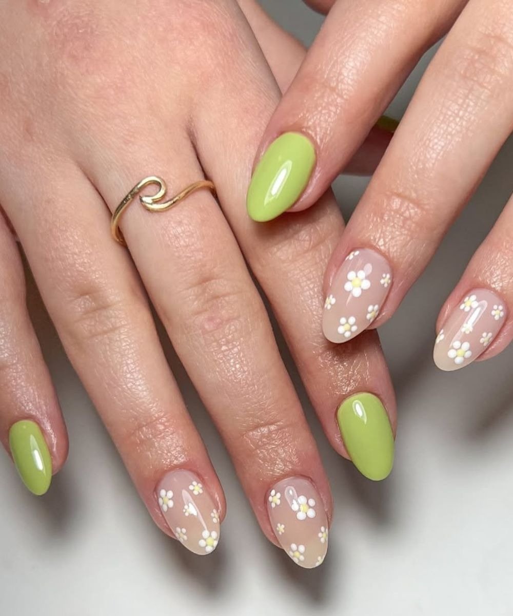 Unhas para o natal e ano novo com esmalte verde vibrante e delicadas flores brancas em fundo nude.