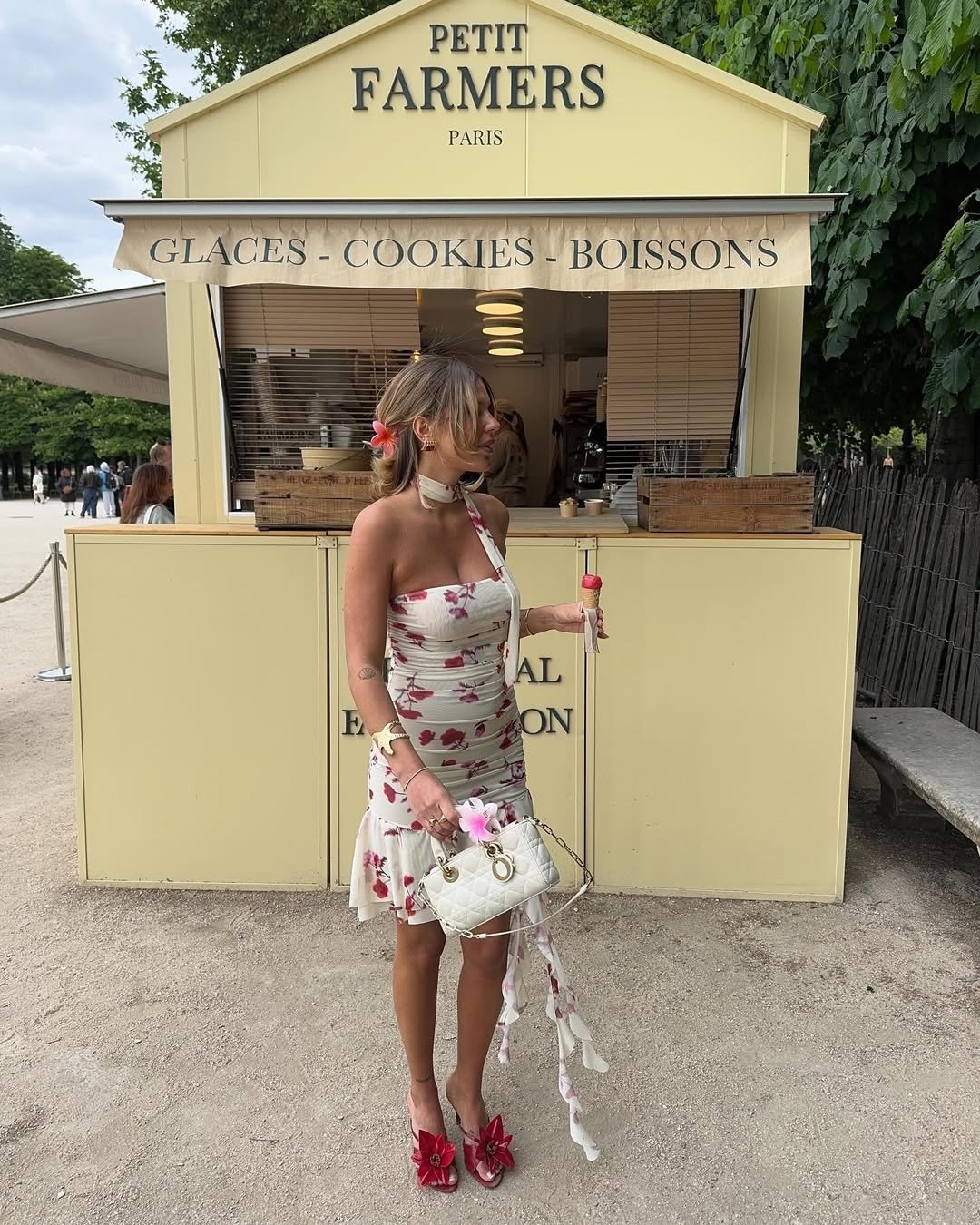 Vestido feminino curto tomara que caia com estampa floral rosa, tecido leve, modelo posa segurando sorvete e bolsa branca.