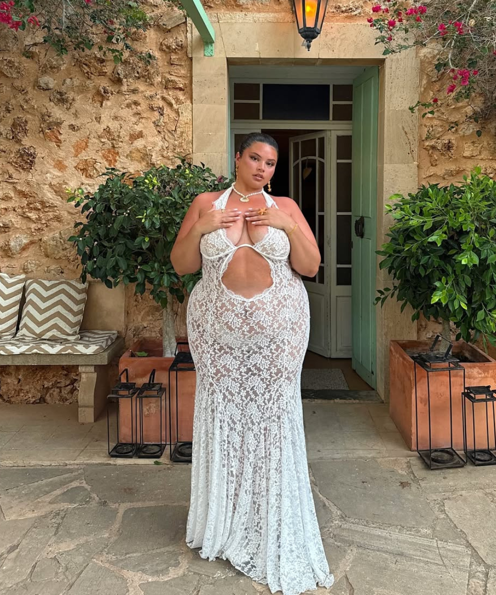 Um vestido branco de renda, com decote profundo e recortes laterais, destaca a silhueta de forma elegante. O modelo é ideal para o Réveillon, combinando sensualidade e sofisticação.