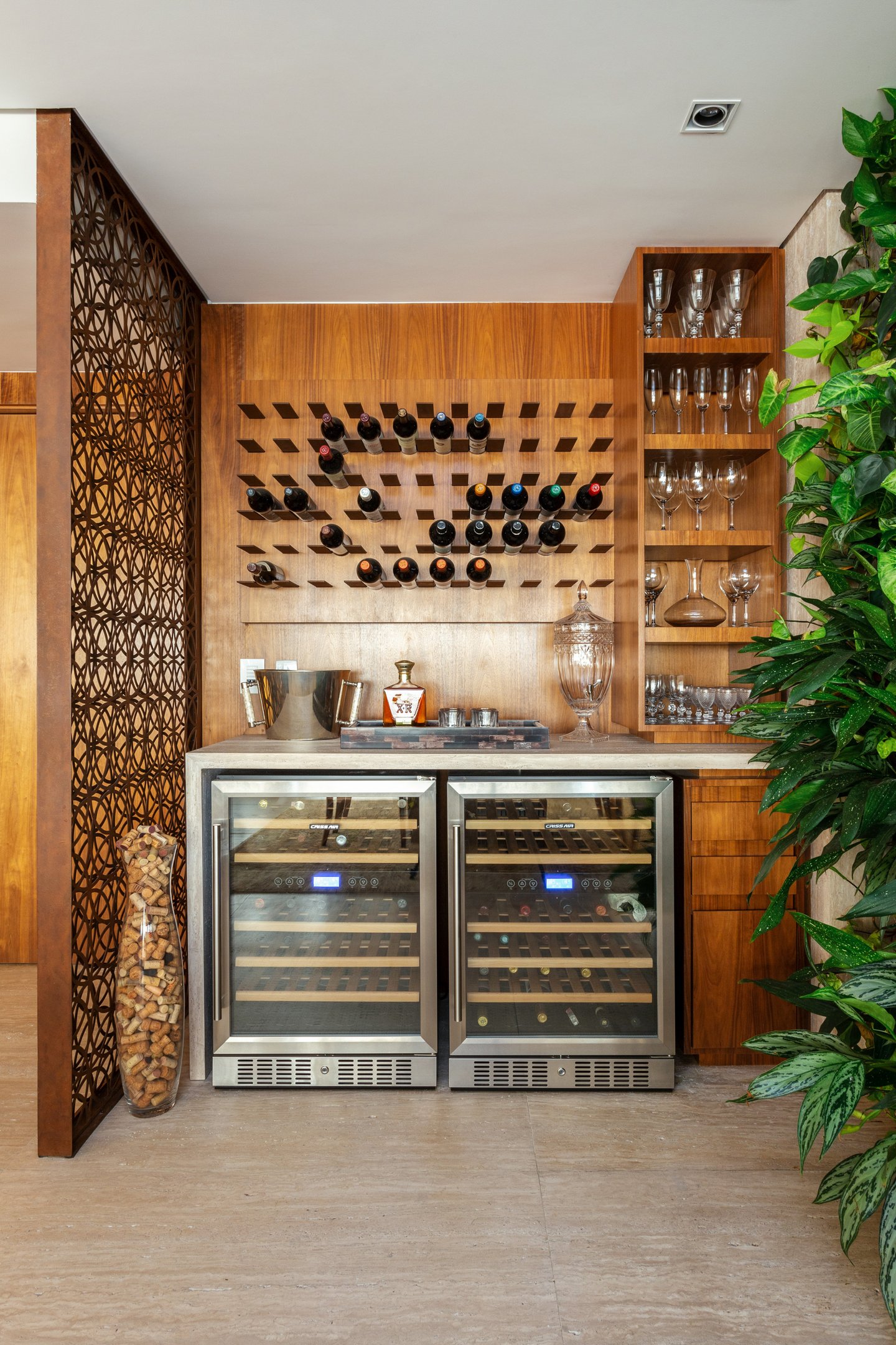 Ambiente sofisticado para Natal em casa com adega embutida, madeira clara, detalhes em vidro e plantas verdes.