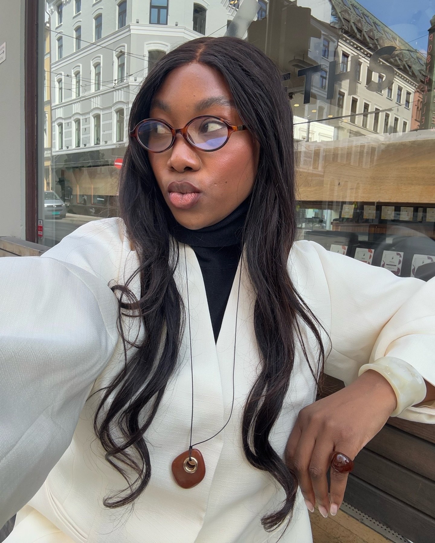 Modelo posa com acessórios que vão bombar em 2026: colar de resina marrom, anel e pulseira em tom off-white, combinados a