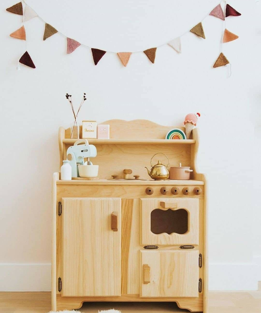 Brinquedos de madeira em tom natural com design lúdico, incluindo mini cozinha e decoração suave em tons terrosos.