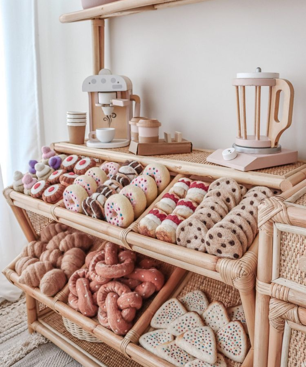 Brinquedos de madeira em tons neutros e pastel compõem cenário acolhedor com café e doces artesanais simulados.