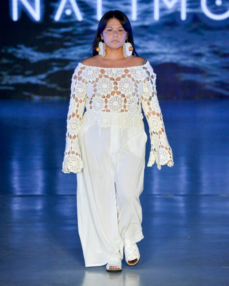 Modelo caminha na Casa de Criadores 57 com blusa branca de crochê floral ombro a ombro e calça ampla fluida, em clima sereno