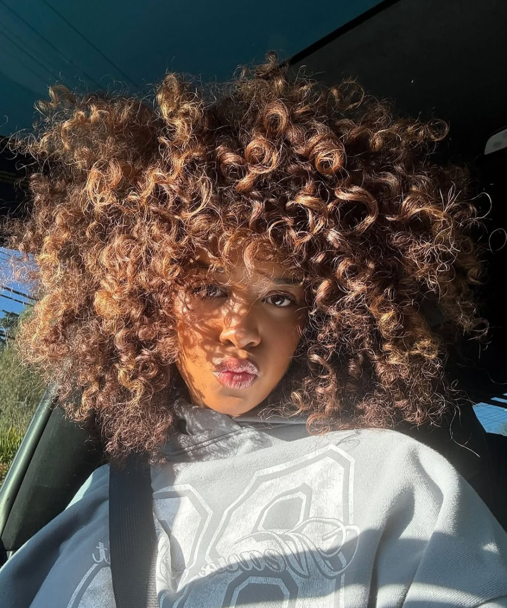 Cortes de cabelo das celebridades ganham destaque com cachos volumosos e naturais em tons castanho iluminado.