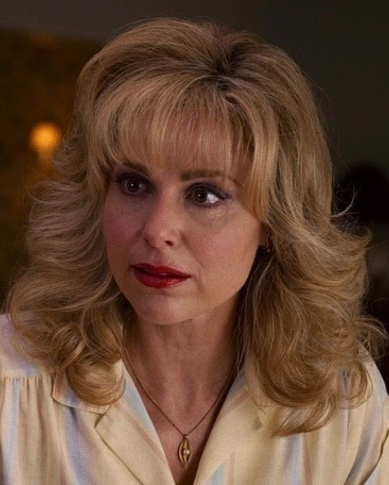 Corte de cabelo de Stranger Things com volume e camadas onduladas em tom loiro dourado, franja reta e estilo vintage dos