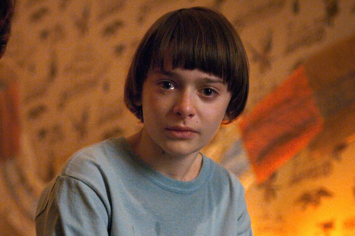 Corte de cabelo de Stranger Things com modelo jovem em blusa azul clara, estilo bowl cut liso e arredondado, clima