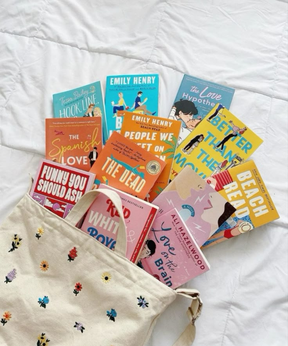 Sacola de algodão cru com bordados florais coloridos exibe capas vibrantes de livros românticos. Dicas de livros de romance.