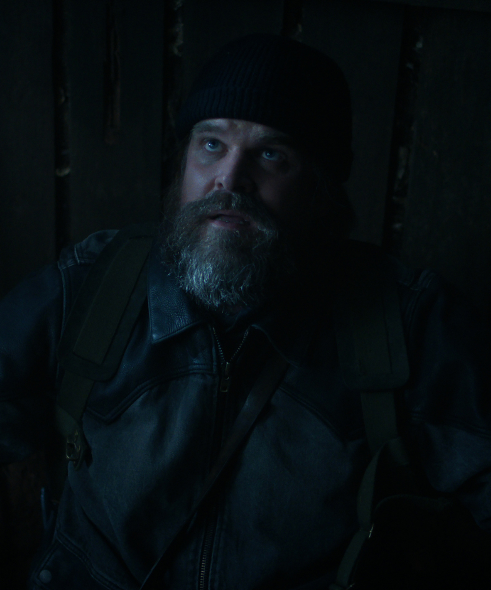 Personagem de Stranger Things usa jaqueta de couro preta, gorro preto e mochila verde-oliva.