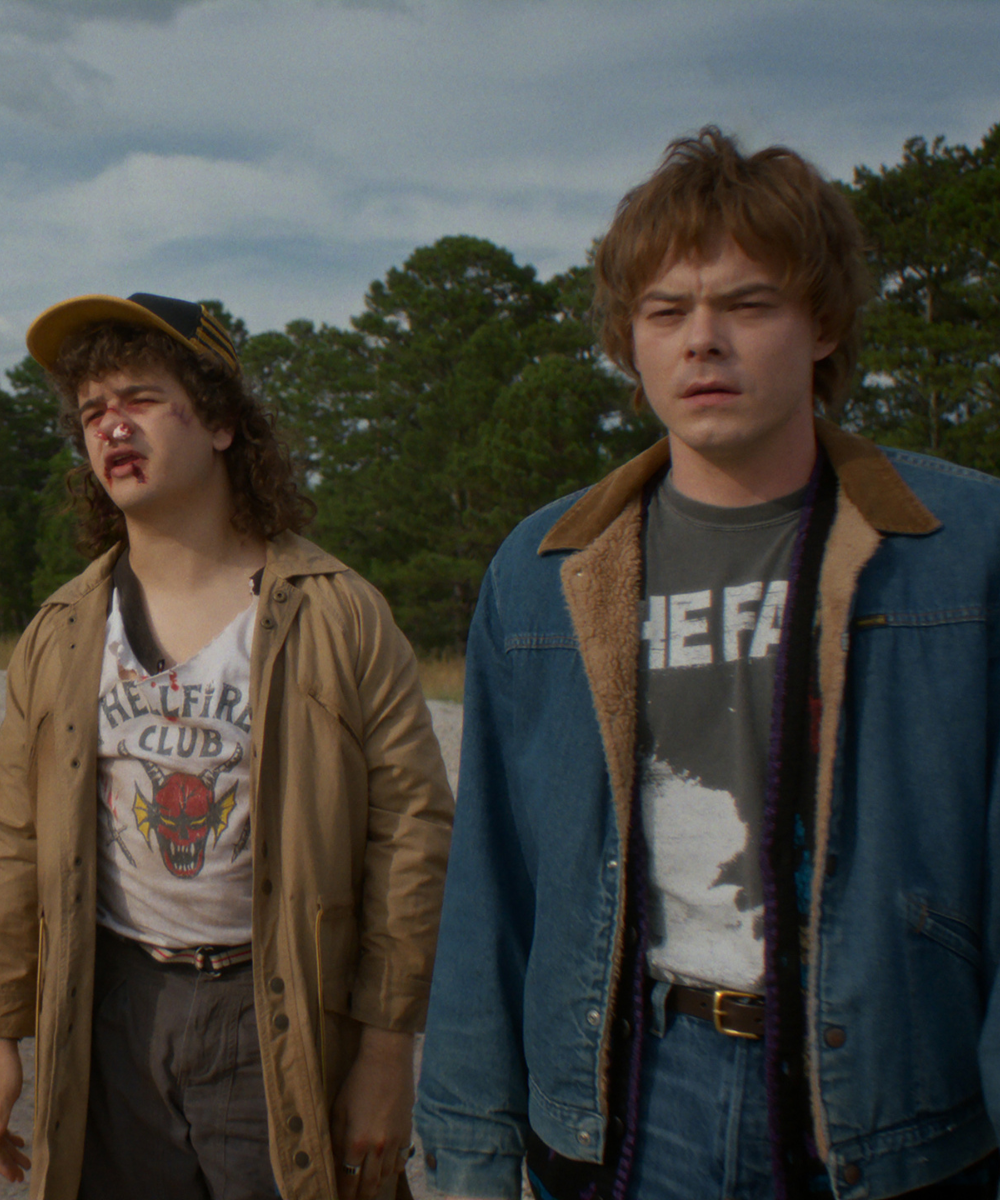 Dois jovens de Stranger Things vestem jaquetas oversized, uma bege e outra jeans com forro de lã.