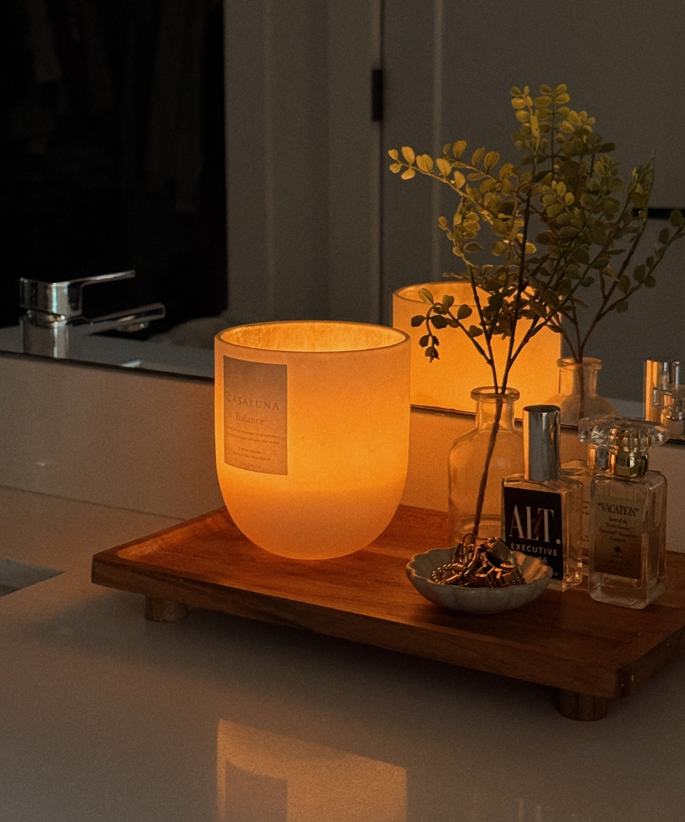 Banho premium com ducha cromada e ramos verdes pendurados, criando ambiente relaxante e natural no banheiro branco.