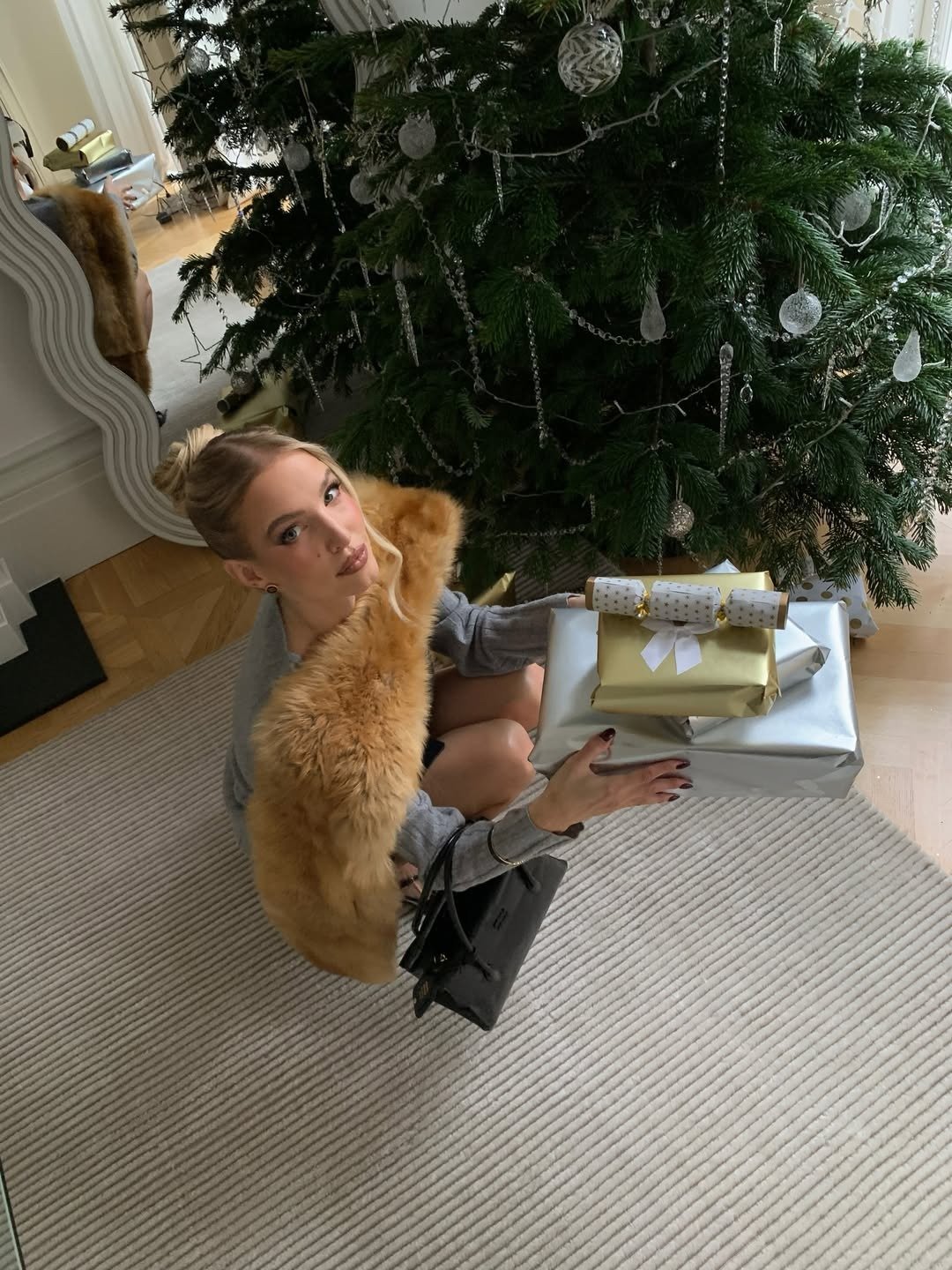 Modelo agacha junto à árvore de Natal decorada com bolas prateadas com Kits de fragrâncias de Natal