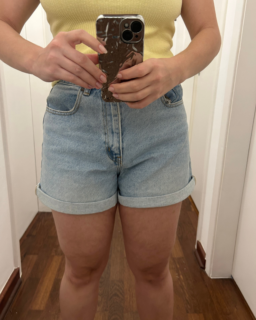 shorts jeans claro de barra dobrada e regata amarela canelada, com resultado do creme firmador 