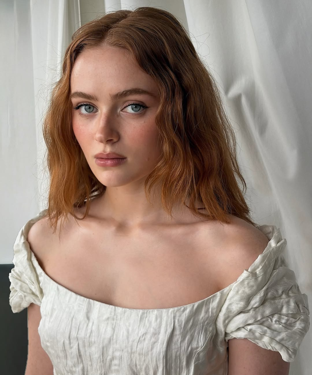 Modelo posa com expressão serena usando blusa off-white de tecido texturizado e mangas bufantes, realçando o lip combo.