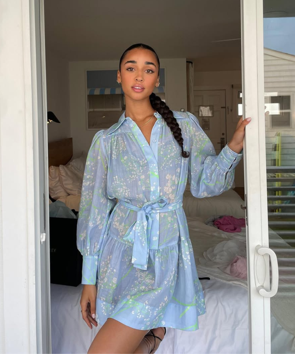 Look com azul em vestido curto fluido de tecido leve com estampa floral, mangas bufantes e cintura marcada por faixa, modelo