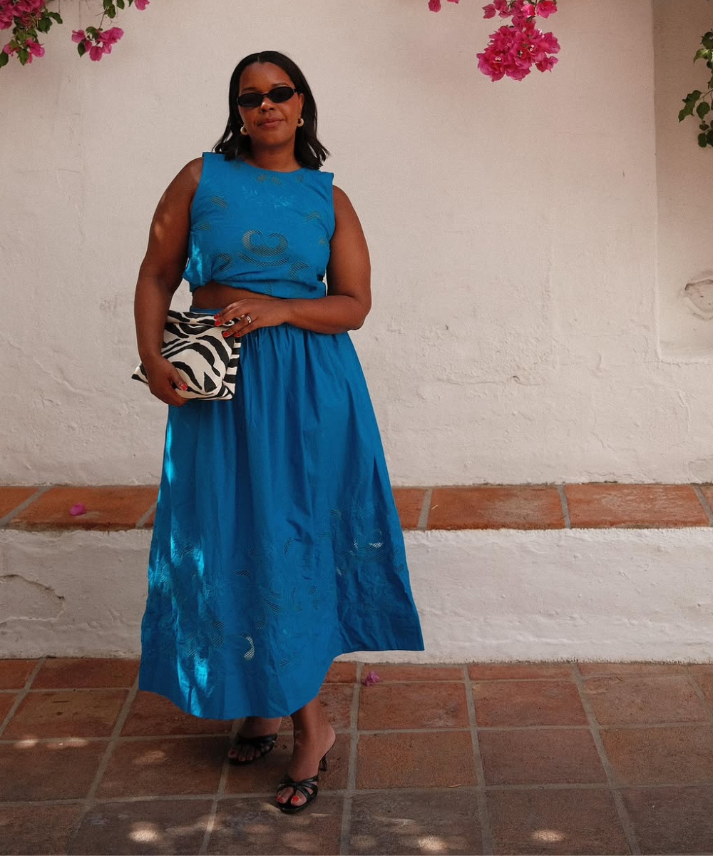 Looks com azul ganham destaque com vestido midi de tecido leve e recortes vazados, combinando clutch animal print e sandália.