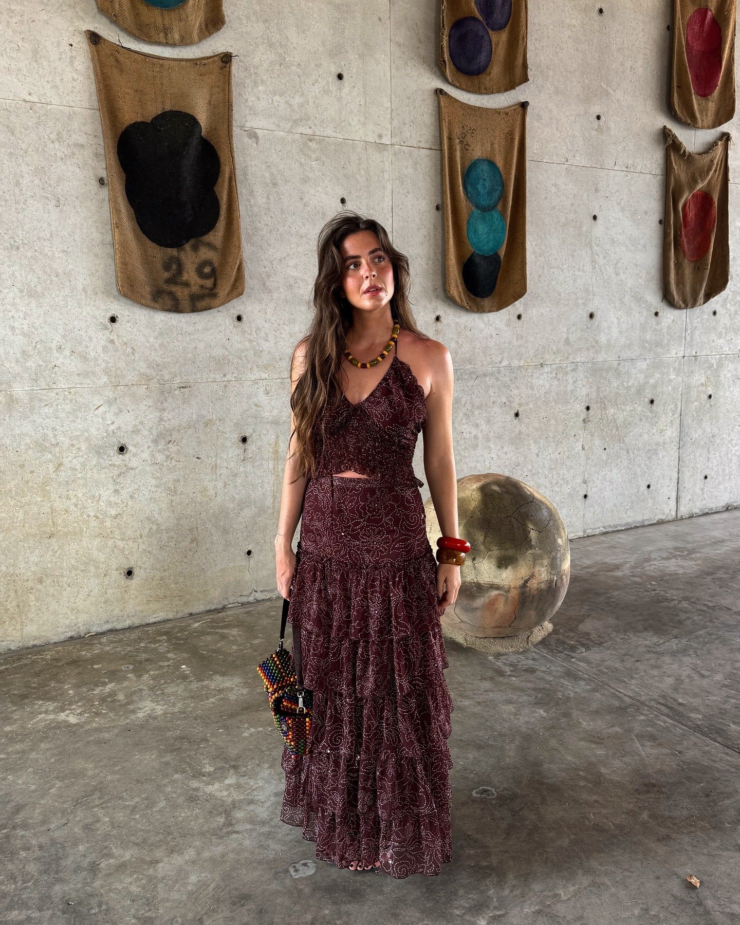 Modelo posa com look elegante para o verão em conjunto bordô de tecido leve com cropped de alças finas e saia longa de