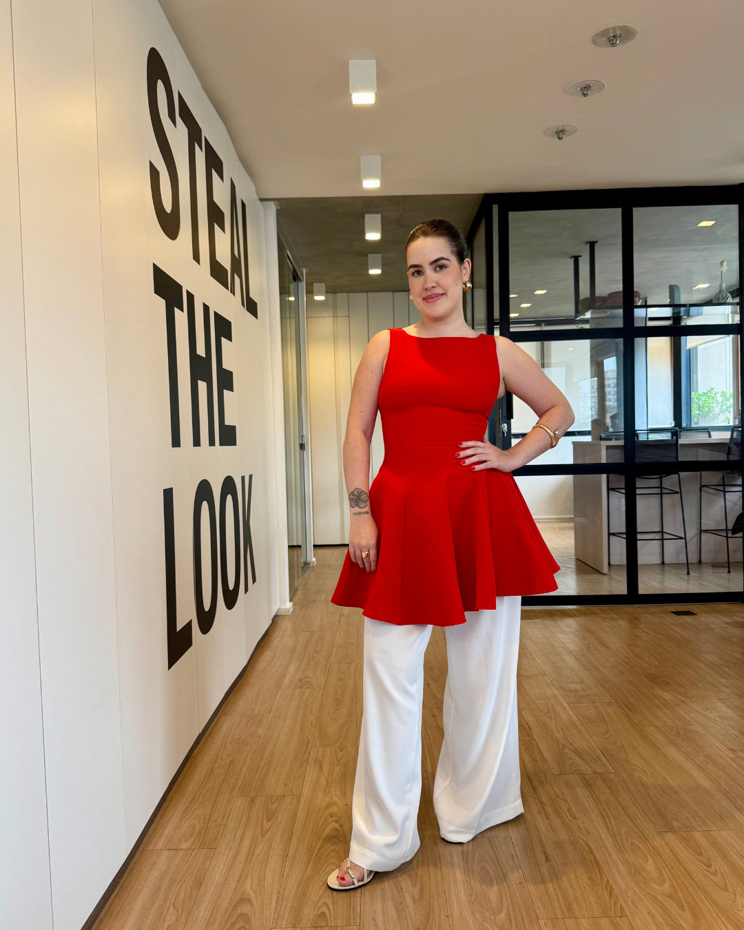 Modelo usando blusa vermelha estruturada e pantalona branca fluida, inspiração de looks estilosos para o fim de ano