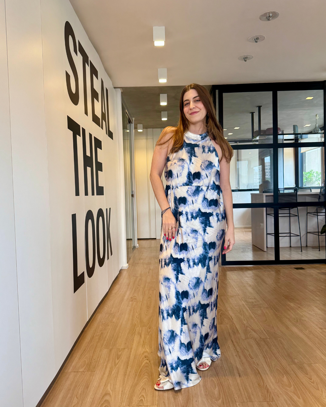Modelo posa sorridente com vestido longo fluido tie-dye azul e branco, inspiração de looks estilosos para o fim de ano