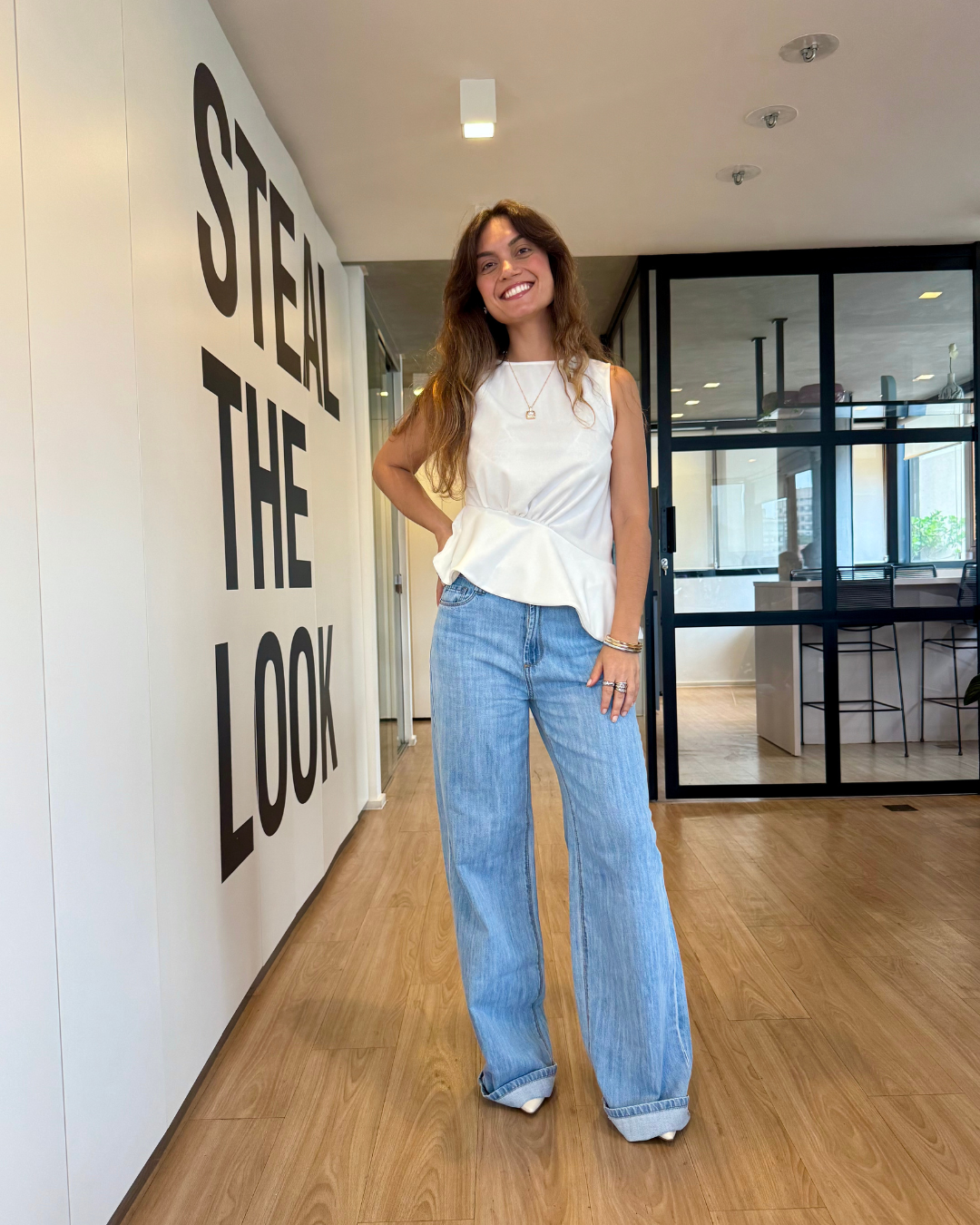 Modelo com blusa branca e calça jeans ampla azul clara, inspiração de looks estilosos para o fim de ano