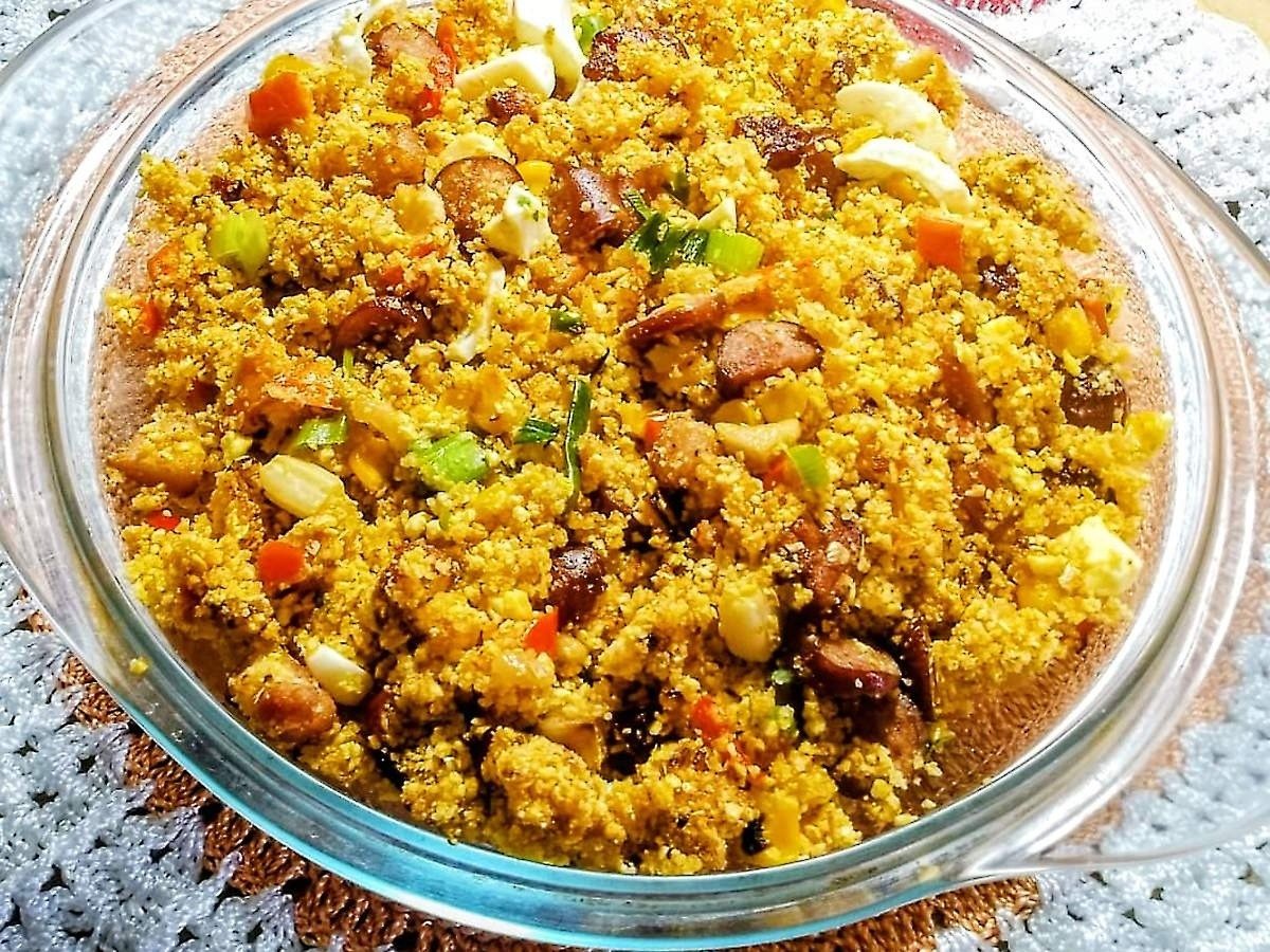 Farofa colorida com linguiça, ovos e legumes em travessa de vidro sobre toalha branca e marrom, sugestão prática do que