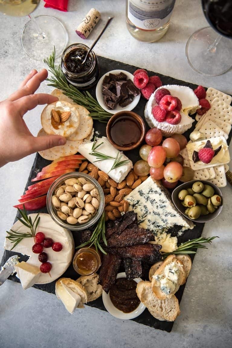 Mesa com tábua de queijos variados, frutas, castanhas e geleias em tons naturais, sugerindo o que fazer na ceia de Natal com