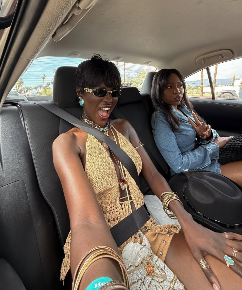 Modelo posa animada usando óculos tendência 2026 com armação retangular preta e detalhes dourados, combinando top de crochê.