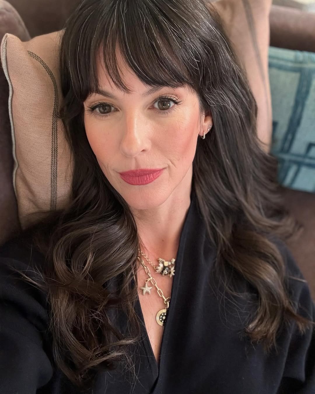 Mulher com cabelo castanho ondulado e franja, veste blusa preta de tecido leve, com pele madura ideal para PDRN vegano