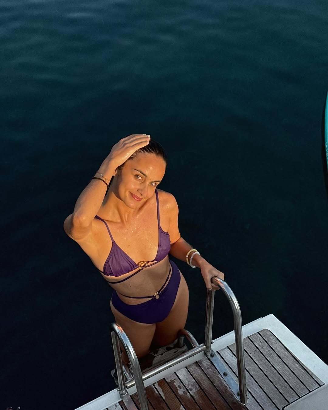 Modelo usando biquíni roxo usando protetor solar multifuncional