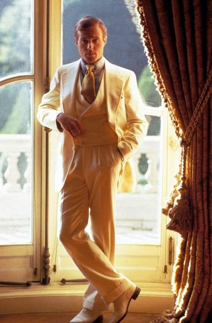 Modelo posa com elegância em terno creme Ralph Lauren de corte clássico, colete e gravata larga, criando clima sofisticado.