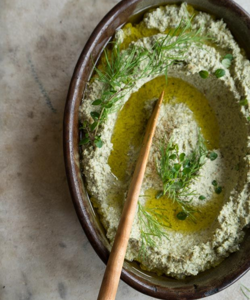 Patê cremoso verde com azeite e ervas frescas em tigela rústica, ideal para receitas para o Ano Novo saudáveis e elegantes.