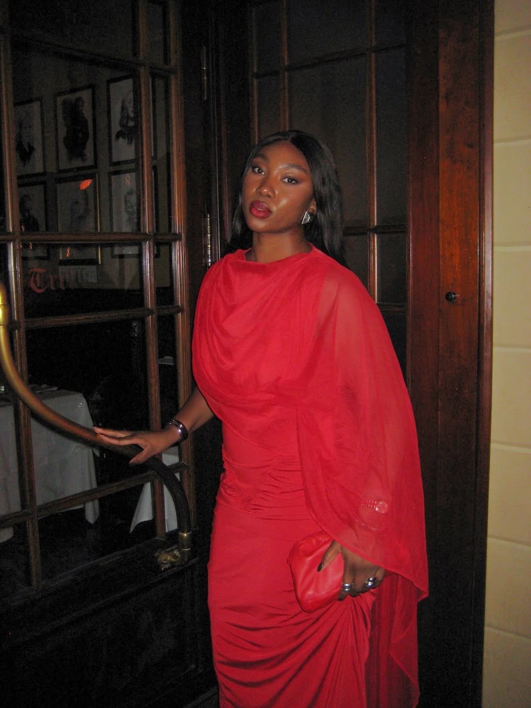 Modelo posa com vestido vermelho drapeado e fluido, look para usar com sapatos confortáveis para festas de fim de ano