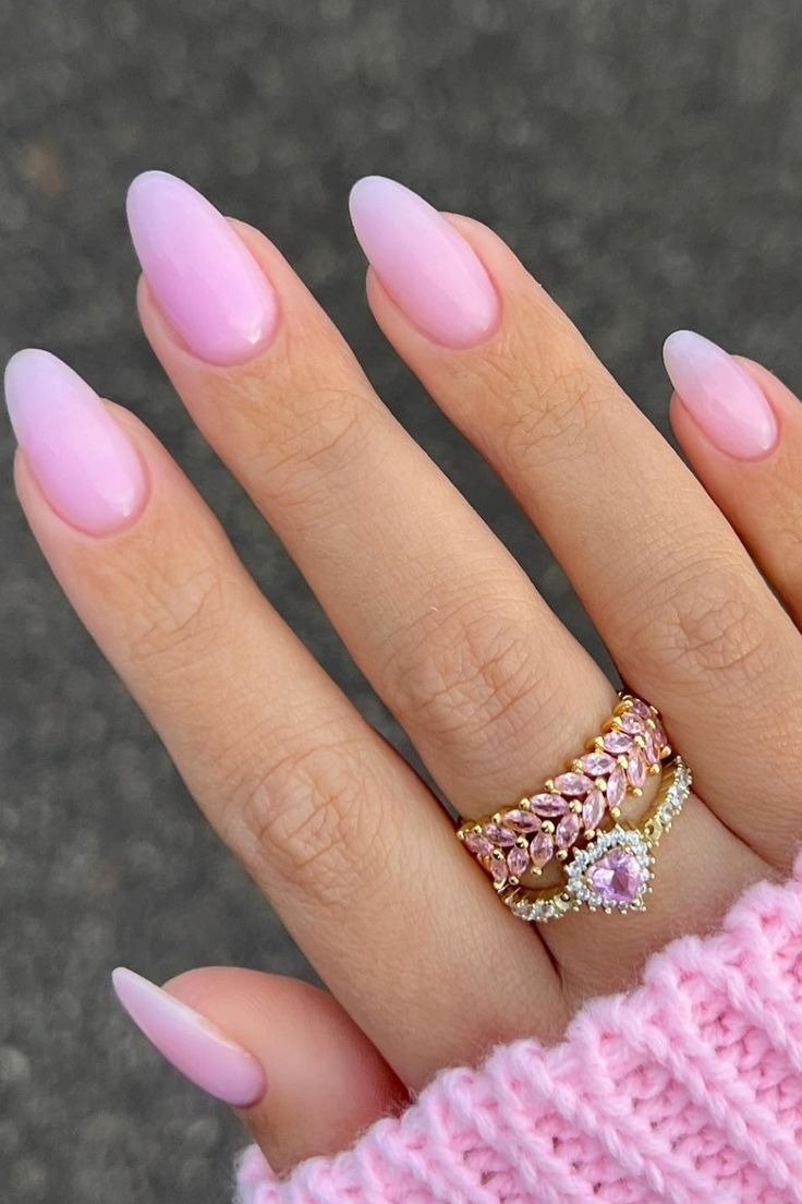 Unhas para Ano Novo em tom rosa suave com acabamento fosco, combinando com anéis delicados e suéter de tricô rosa.
