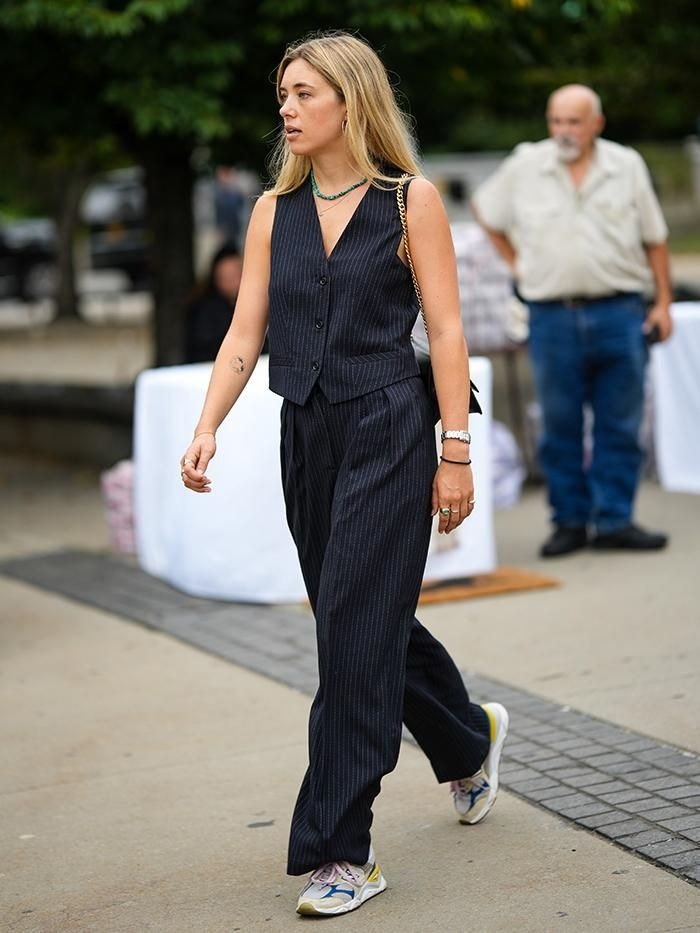 looks com tênis esportivo --Modelo caminha com postura confiante usando colete e calça pantalona risca de giz em tecido