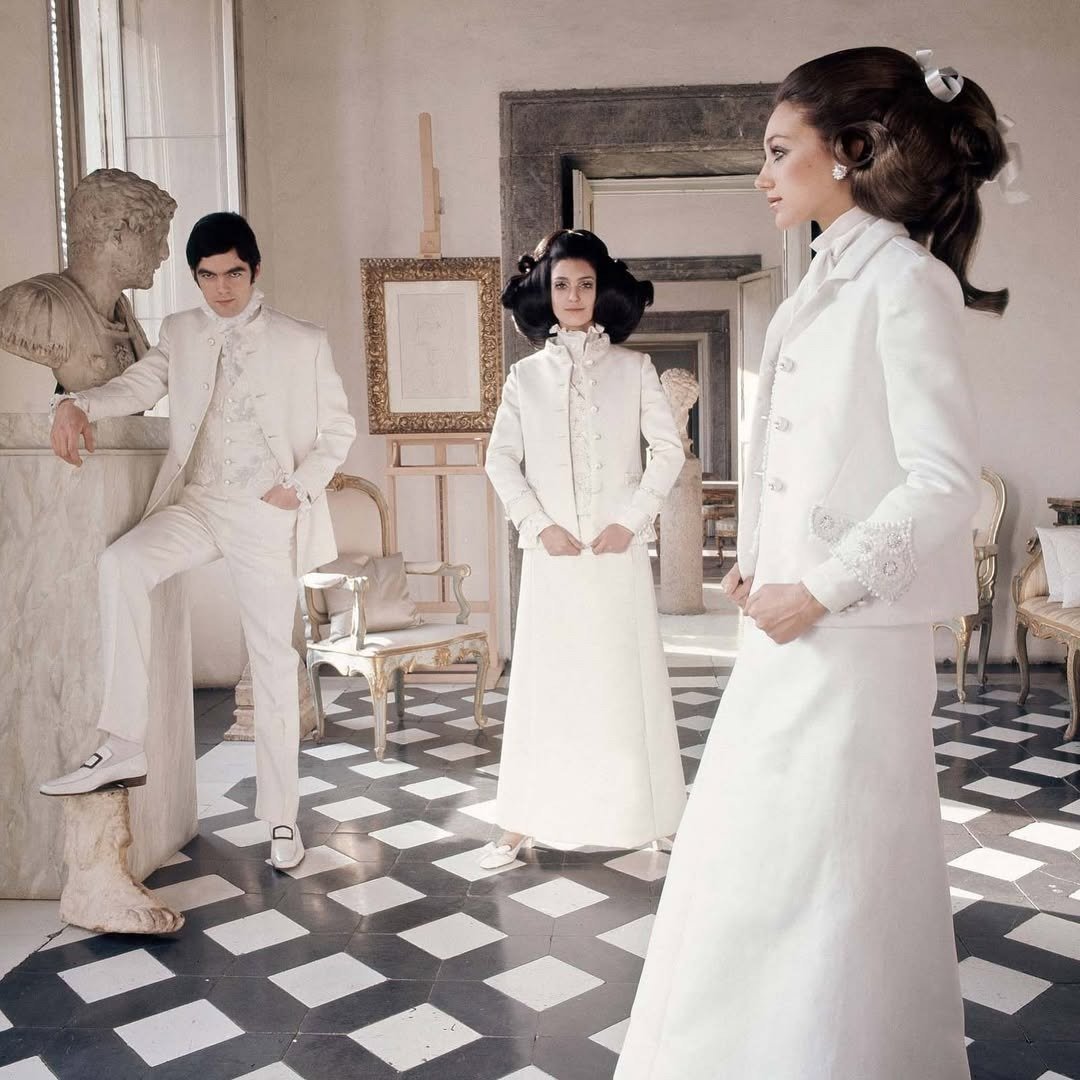 Modelos posam em ambiente clássico usando peças Valentino brancas com cortes retos, detalhes bordados e tecidos