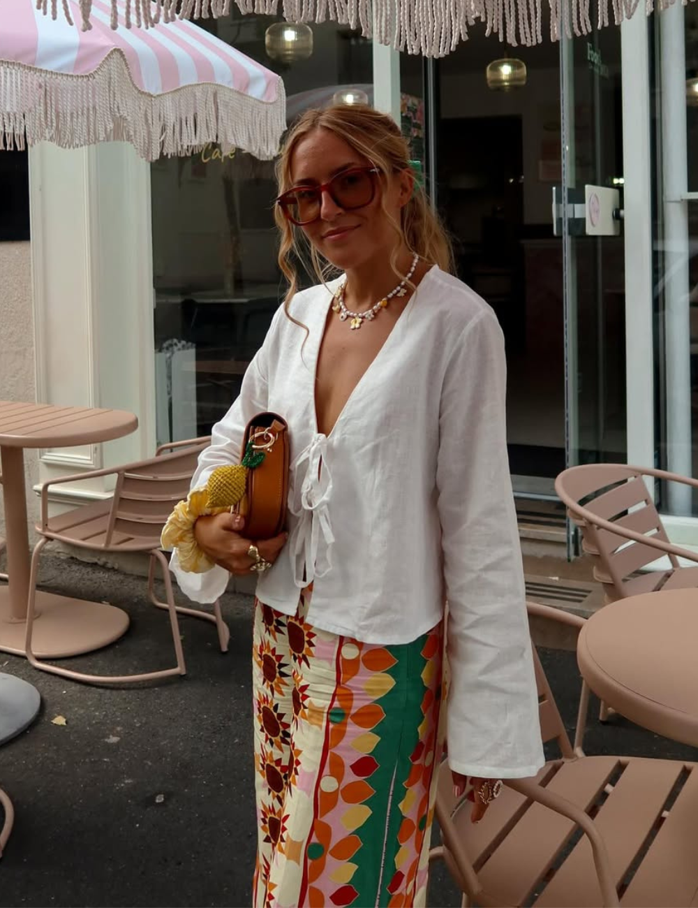 Modelo posa com bata feminina branca de linho, mangas amplas e amarração frontal, combinada a saia colorida vibrante.