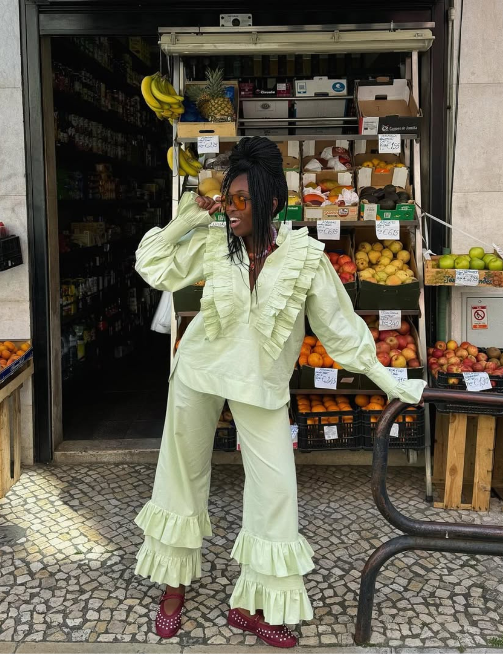 Modelo posa com bata feminina verde clara de algodão, mangas bufantes e babados, combinada com calça ampla e sapatos