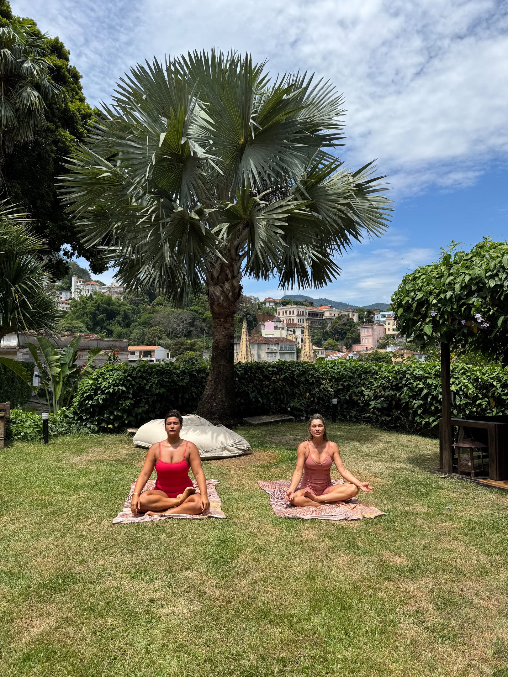 Duas mulheres em maiôs rosa e vermelho fazendo ioga, trazendo os questionamentos sobre bullying na infância