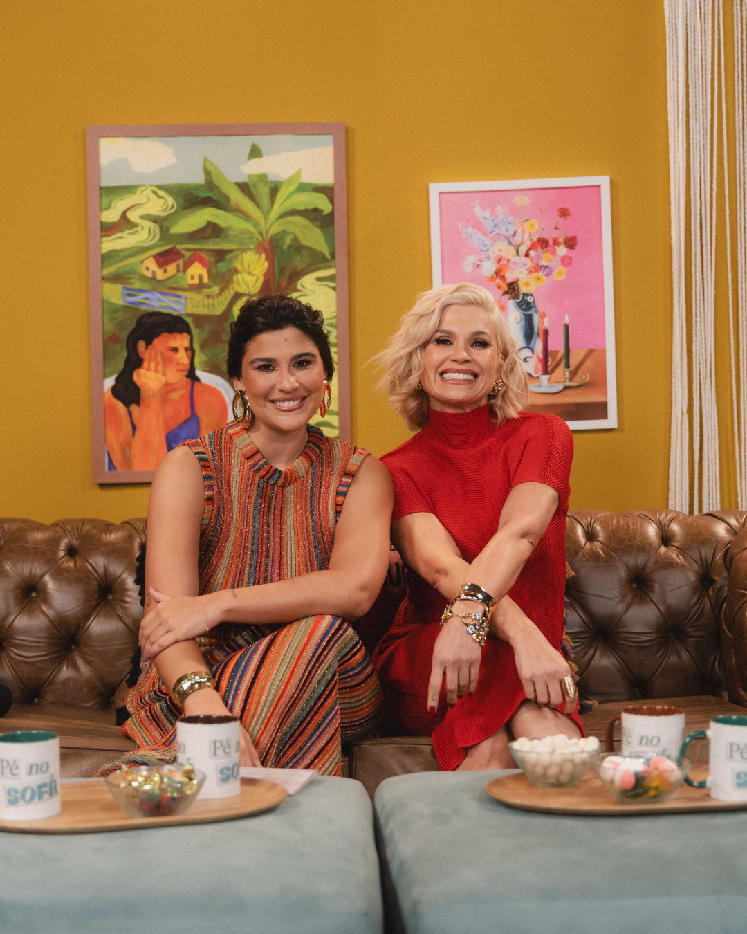 Duas mulheres em sofá marrom, enquanto discutem sobre bullying na infância no podcast Pé no Sofá