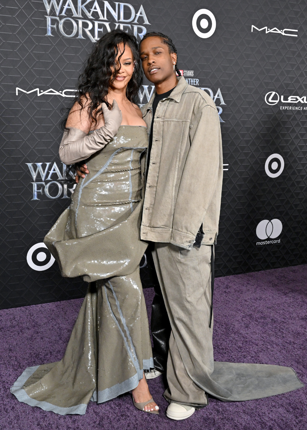 Casal de Hollywood posa abraçado com vestido longo verde oliva brilhante e luvas.