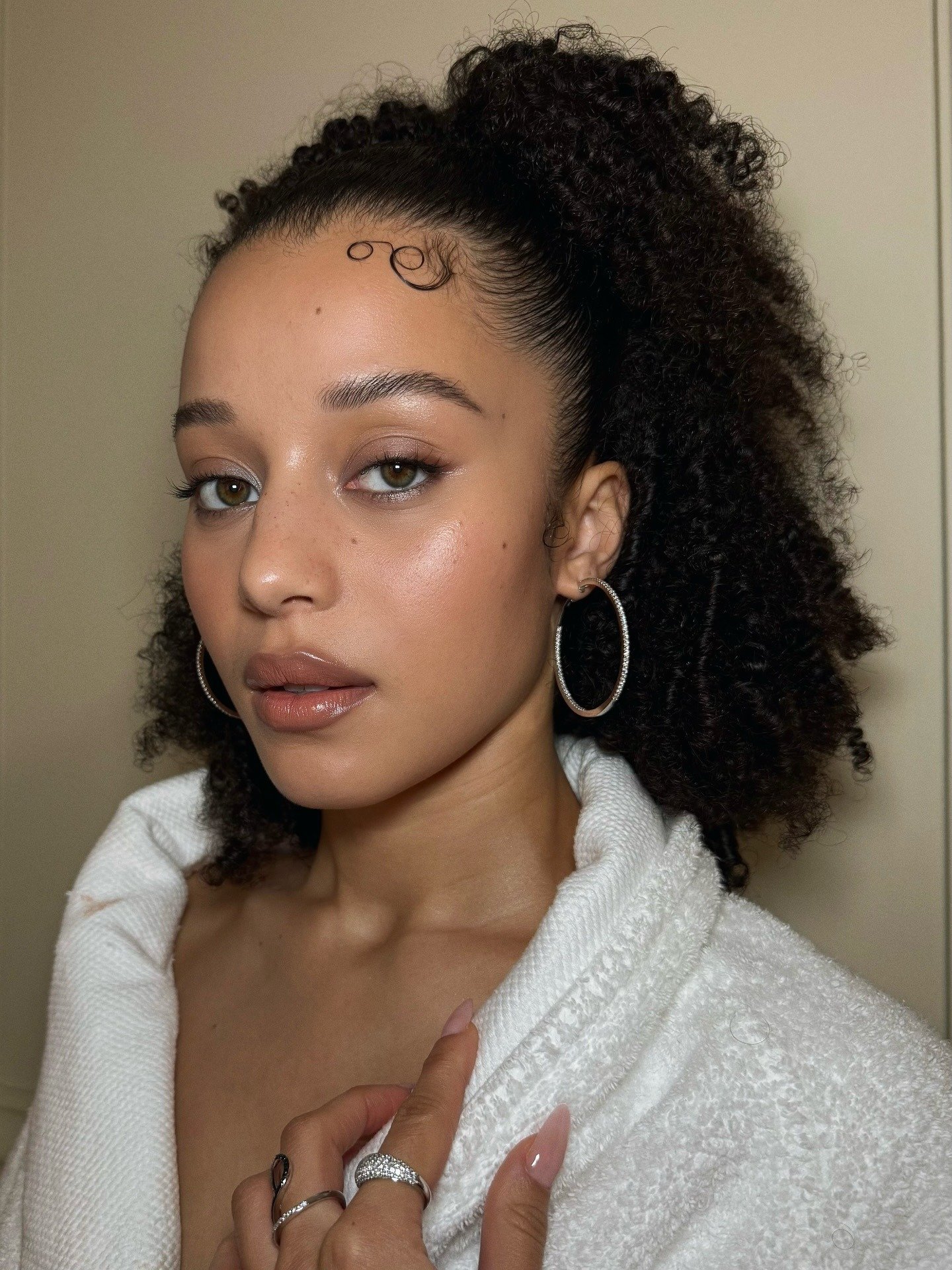 Chase Infiniti exibe look clean com casaco branco texturizado, brincos de argola prateados e maquiagem natural