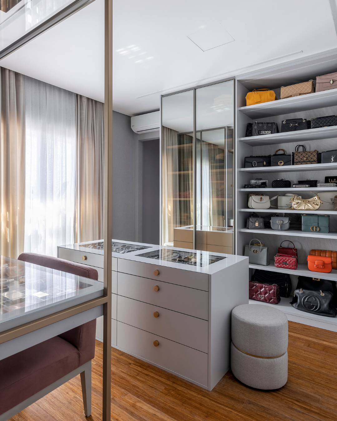 como organizar o closet com armário branco, espelhos amplos, estantes de bolsas coloridas e iluminação natural suave para