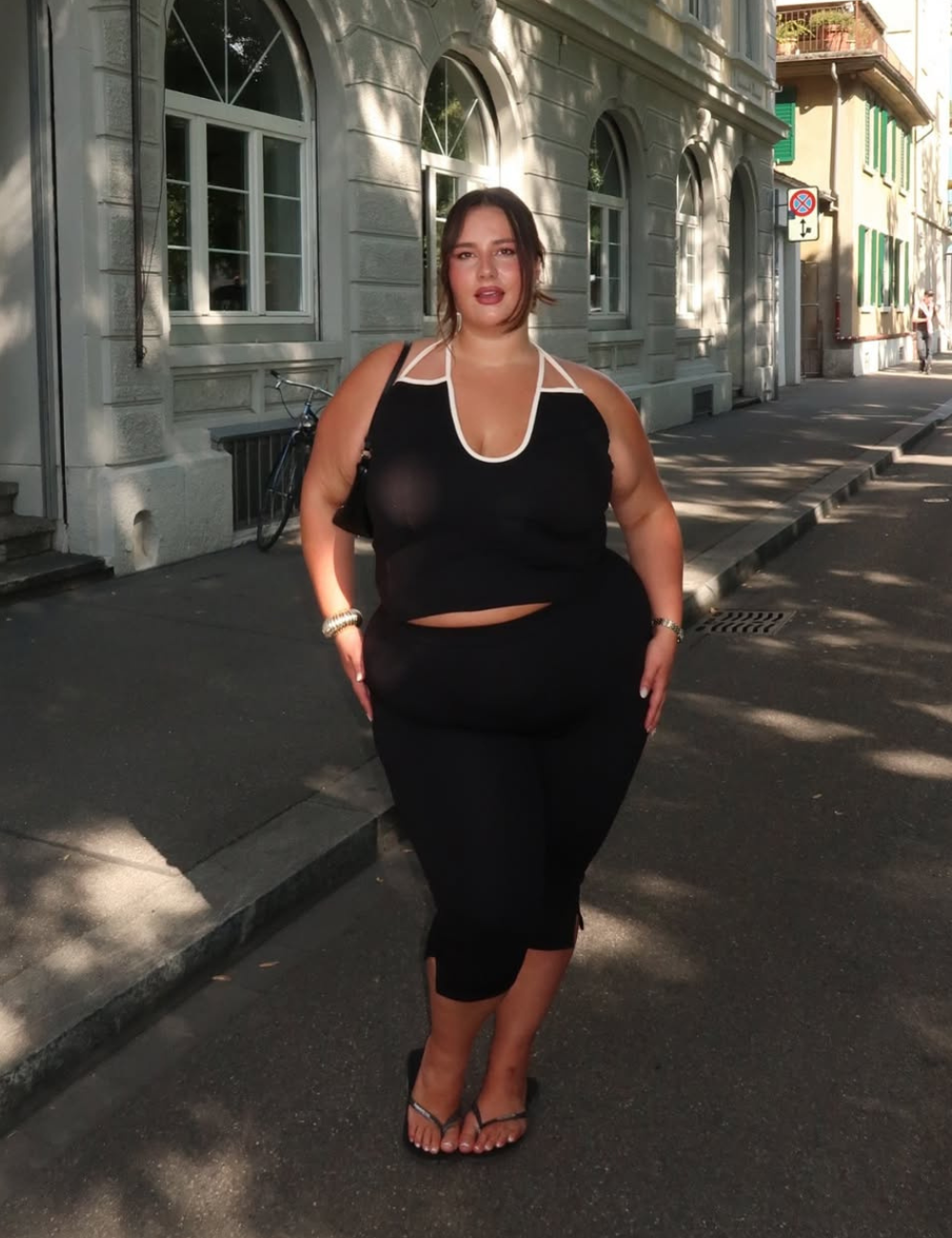 Modelo posa com conjunto preto de regata e bermuda, combinando conforto e estilo para aprender como usar preto no verão.