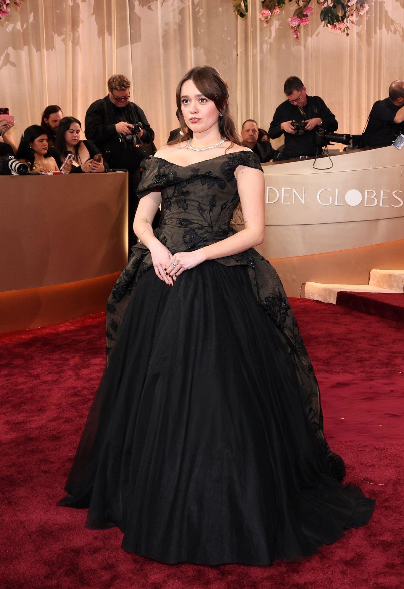 Modelo posa com vestido preto de tule e corpete bordado com decote ombro a ombro, em clima elegante no Globo de Ouro 2026.