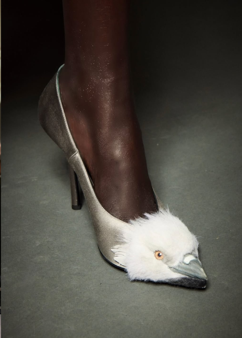 Scarpin prata com salto fino e bico decorado por cabeça de pássaro branco em textura felpuda destaca tendências da temporada