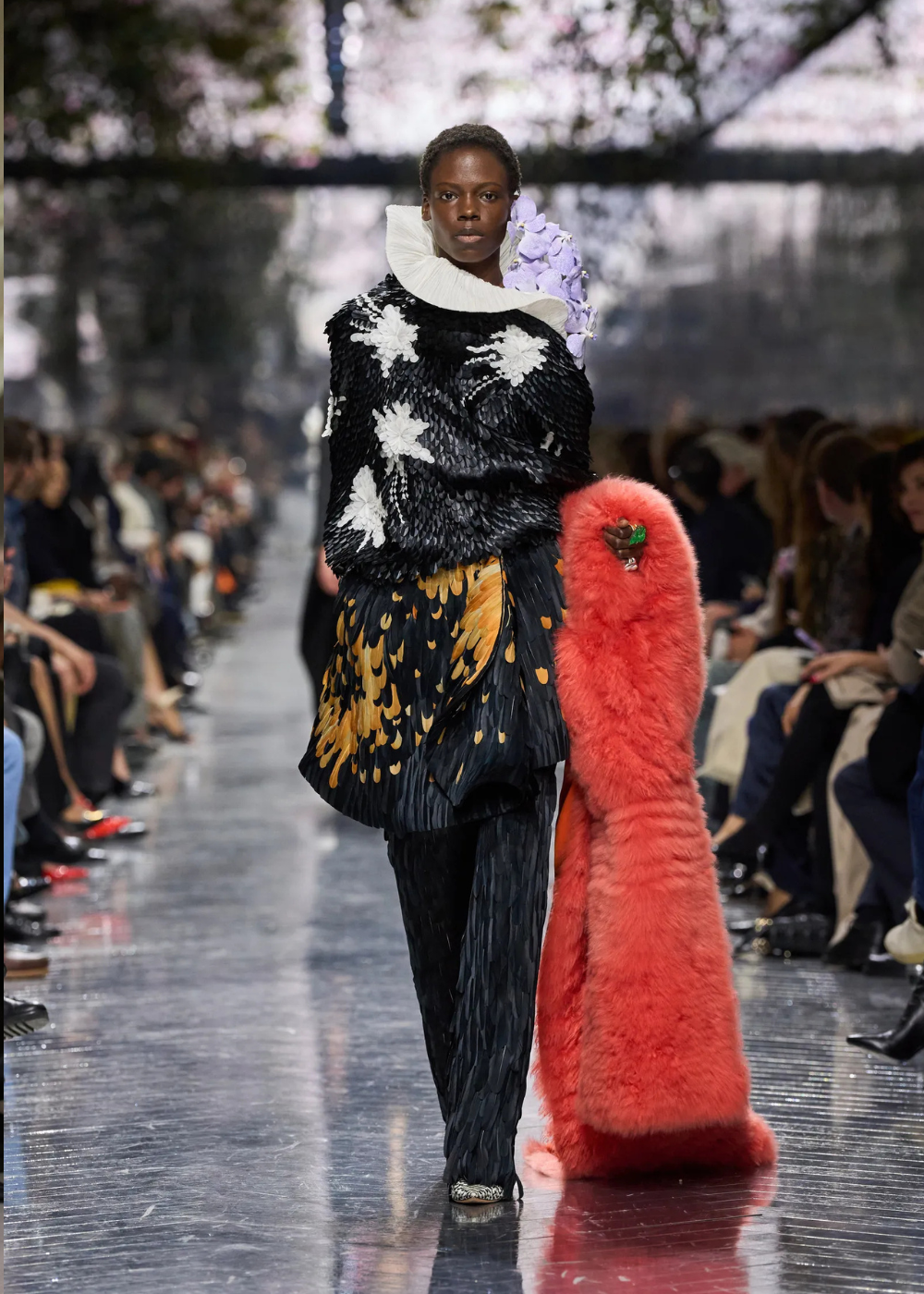 Modelo desfila com look de alta-costura primavera 2026, combinando texturas plissadas e bordados florais em preto, branco e