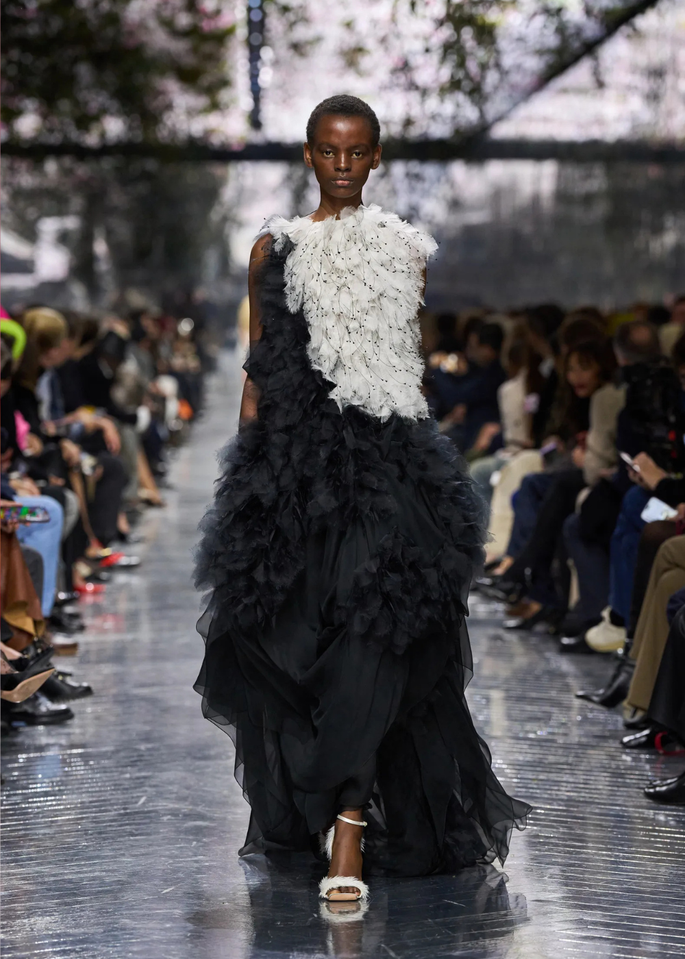 Modelo caminha com vestido bicolor preto e branco em tule texturizado, destacando as tendências da temporada de alta-costura