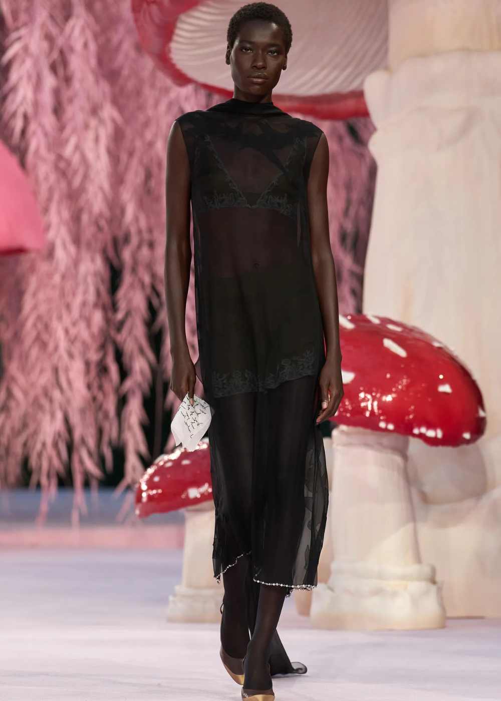 Modelo caminha com vestido preto transparente em tecido leve e fluido, destacando tendências da temporada de alta-costura